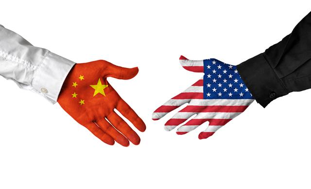 hands covered in Chinese and American flags shaking